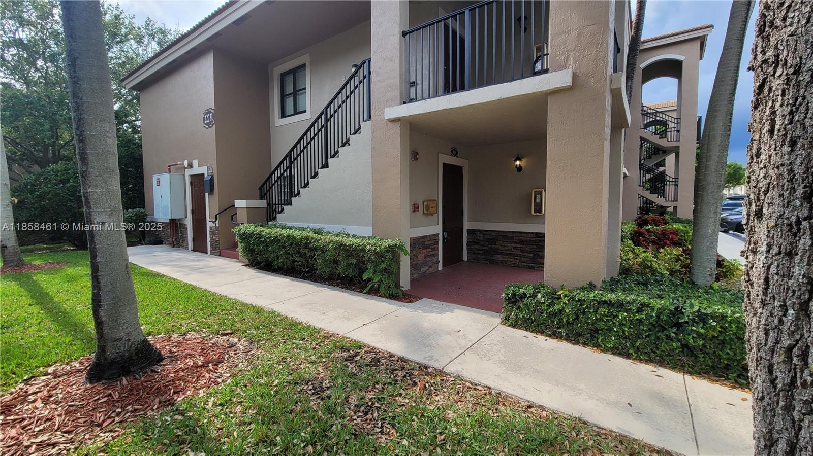 22731 Southwest 88th Place, Unit 101 Cutler Bay, FL 33190 - Photo 3 of 59 a view of a house with a small yard plants and large tree