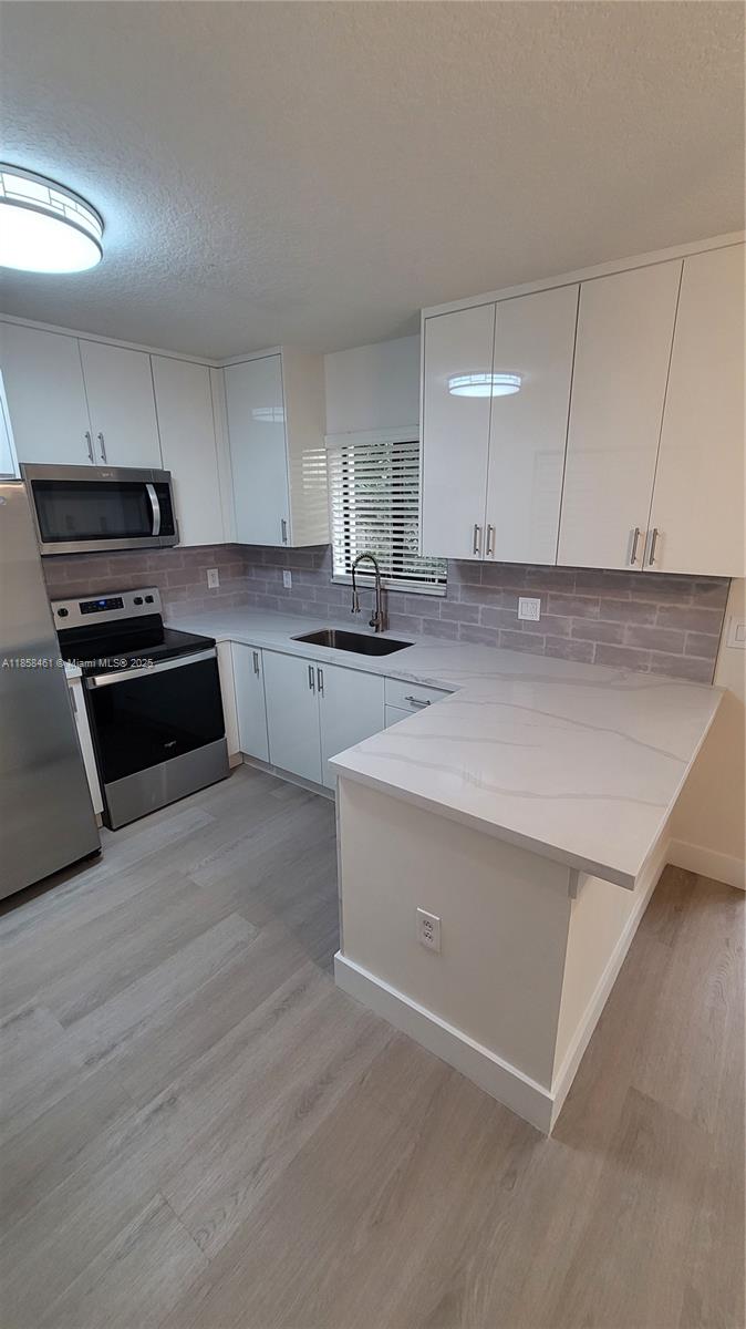22731 Southwest 88th Place, Unit 101 Cutler Bay, FL 33190 - Photo 10 of 59 a kitchen with stainless steel appliances granite countertop a stove a sink and a refrigerator