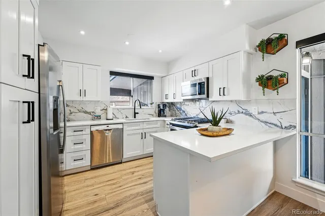 a kitchen with a sink a stove a refrigerator and white cabinets