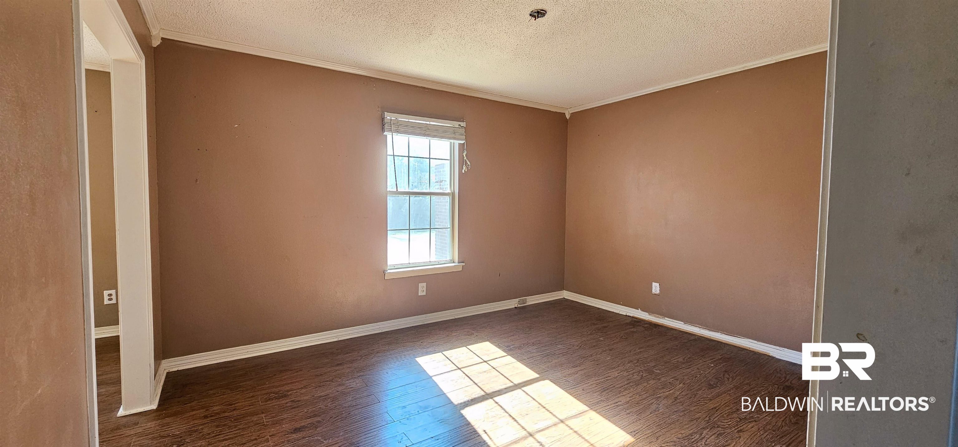 151 Bullard Street Atmore, AL 36502 - Photo 6 of 38 Empty room featuring a textured ceiling, crown molding, and dark wood-style flooring