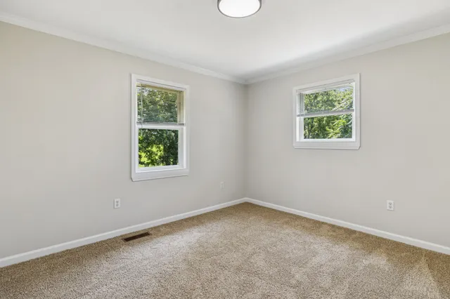 a view of an empty room with wooden floor and closet
