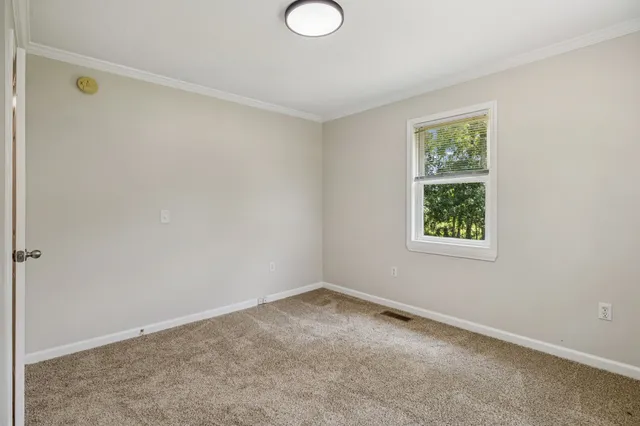a view of an empty room with closet and a window