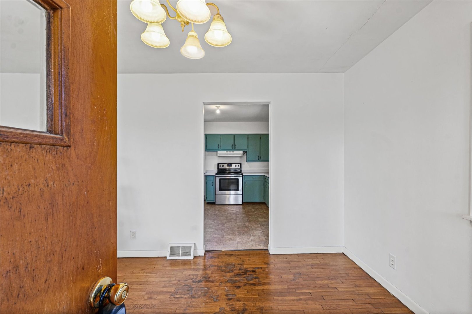 404 South Maple Street Gilman, IL 60938 - Photo 5 of 28 an empty room with wooden floor and kitchen view