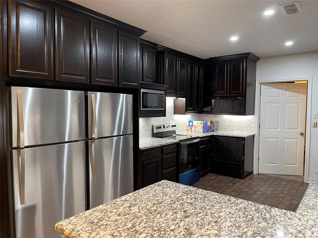 865 Higgins Road Sherman, TX 75092 - Photo 14 of 40 a kitchen with kitchen island granite countertop wooden cabinets and refrigerator