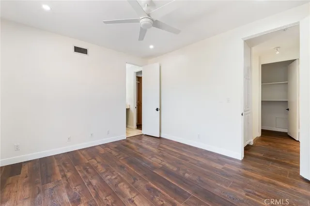 an empty room with wooden floor and a ceiling fan