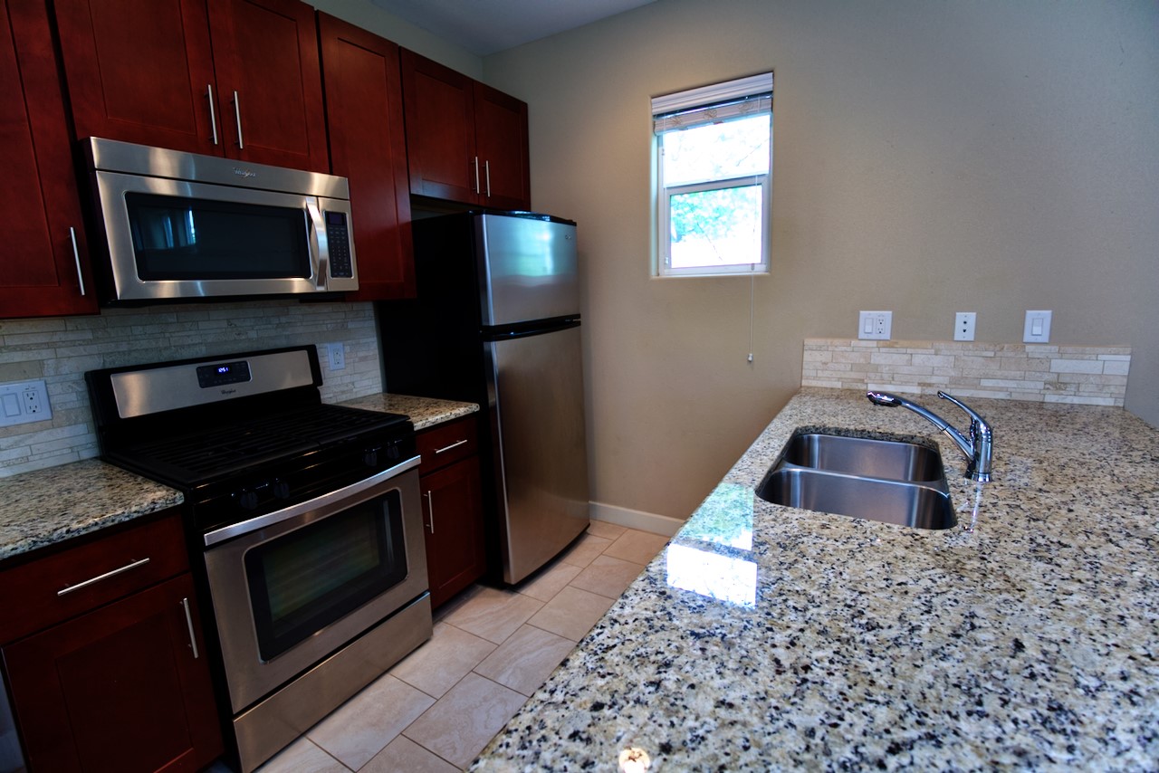1800 Richcreek Road, Unit B Austin, TX 78757 - Photo 4 of 10 a kitchen with granite countertop a stove a microwave a sink and cabinets