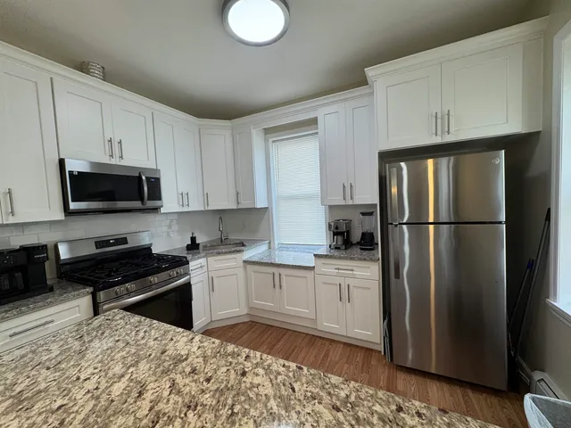 a kitchen with a refrigerator stove and white cabinets