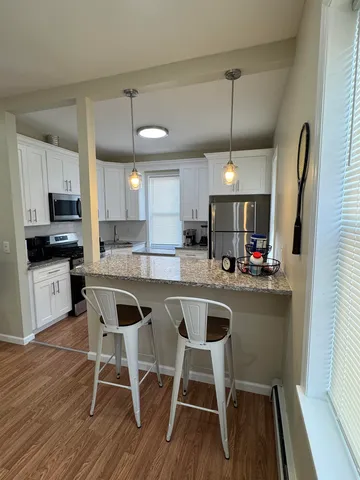 a kitchen with stainless steel appliances granite countertop a stove top oven a sink a dining table and chairs with wooden floor