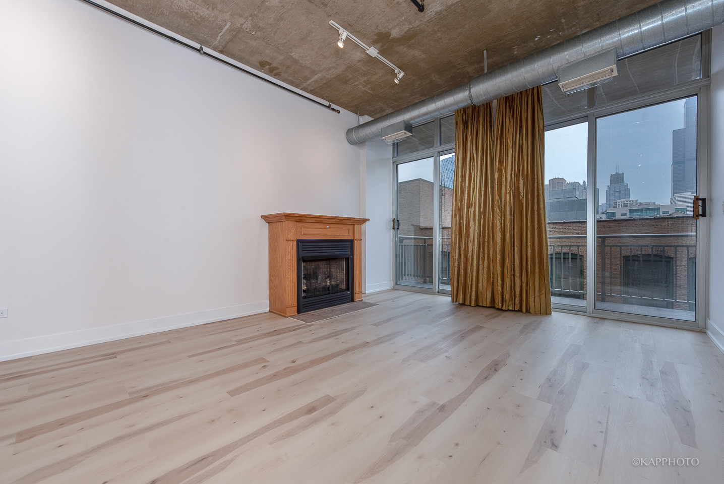 111 South Morgan Street, Unit 619 Chicago, IL 60607 - Photo 9 of 35 an empty room with wooden floor and a fireplace