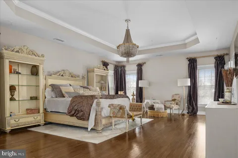a spacious bedroom with a bed a chandelier couches and fireplace