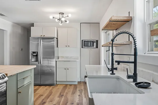 a kitchen with kitchen island a counter top space a sink wooden floor and a refrigerator