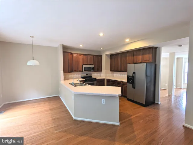 a view of kitchen with stainless steel appliances granite countertop a refrigerator a sink dishwasher a oven and a dining table with wooden floor