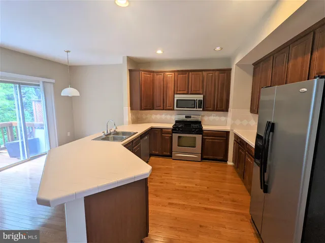 a kitchen with kitchen island a counter top space cabinets stainless steel appliances and a window