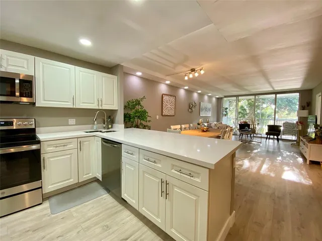 a kitchen with a sink dishwasher a stove and white cabinets with wooden floor