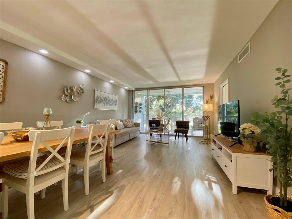 3010 North Course Drive, Unit 209 Pompano Beach, FL 33069 - Photo 11 of 39 a living room with furniture a large window and wooden floor