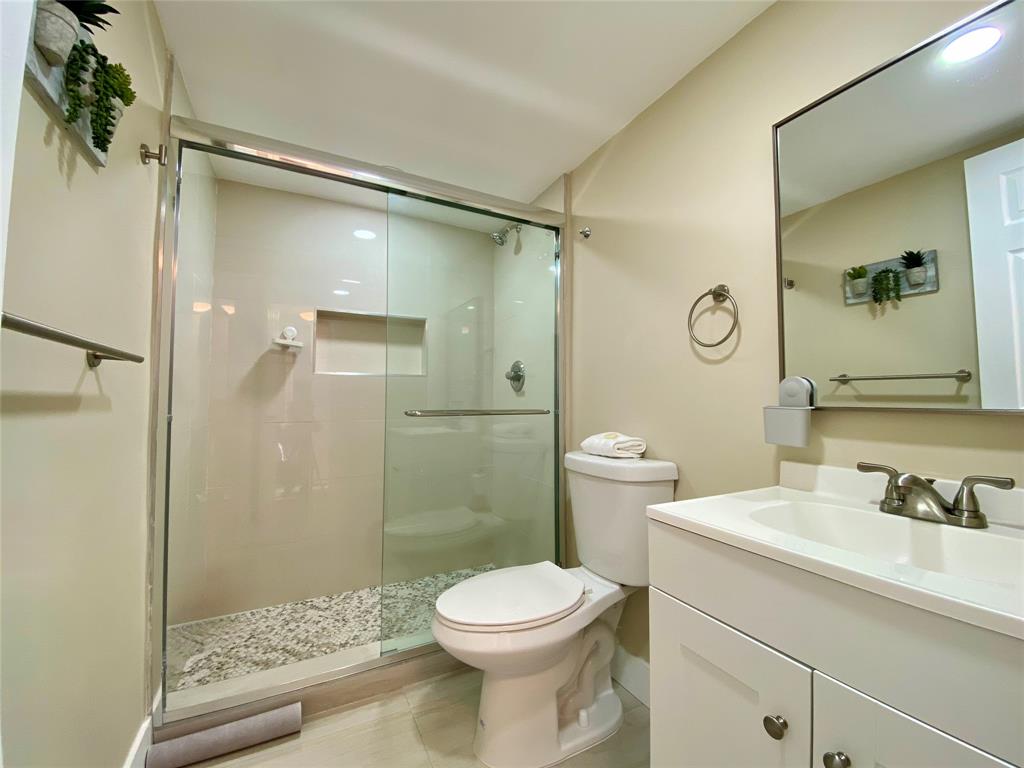 3010 North Course Drive, Unit 209 Pompano Beach, FL 33069 - Photo 19 of 39 a bathroom with a sink a mirror a toilet and shower
