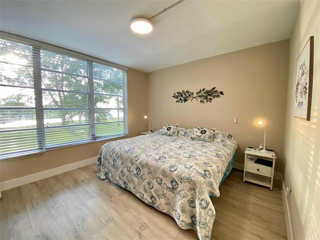 3010 North Course Drive, Unit 209 Pompano Beach, FL 33069 - Photo 22 of 39 a bed sitting in a spacious bedroom next to a window