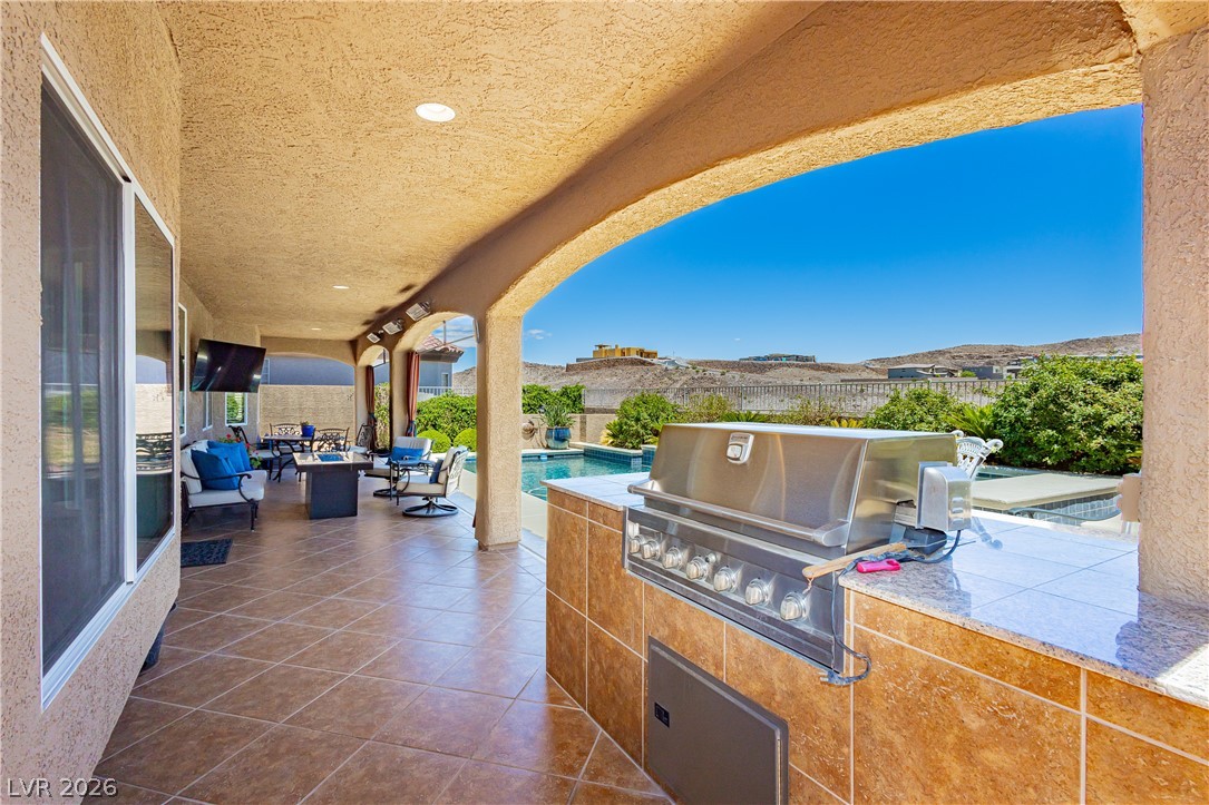 2256 Dogwood Ranch Avenue Henderson, NV 89052 - Photo 43 of 51 An inviting covered patio featuring an outdoor kitchen and a sparkling pool, perfect for leisure.
