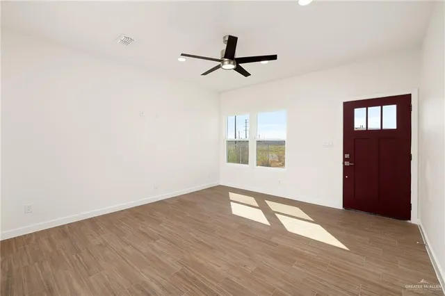 a view of empty room with wooden floor and fan