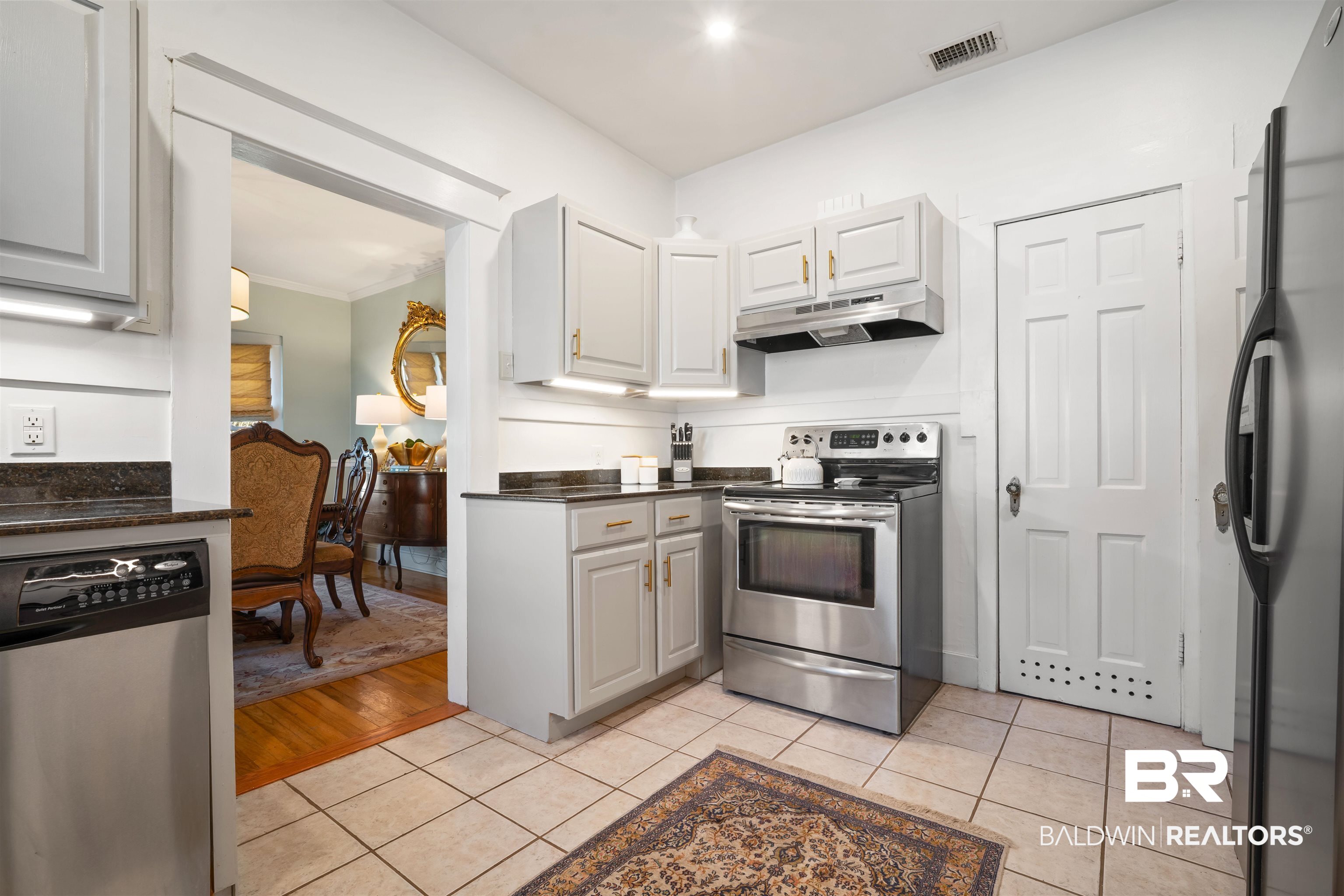 168 Mohawk Street Mobile, AL 36606 - Photo 11 of 31 Kitchen featuring stainless steel appliances, light tile patterned floors, white cabinetry, dark stone countertops, and crown molding