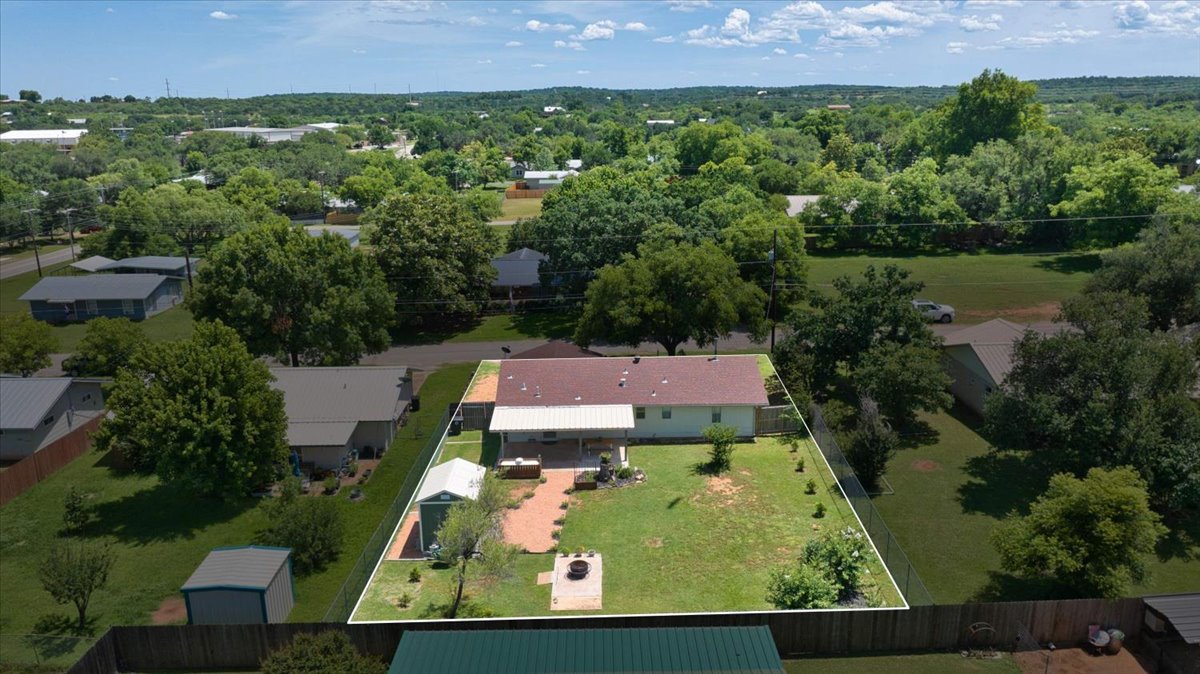 1236 Martin Street Mason, TX 76856 - Photo 34 of 40 An aerial perspective reveals a cozy home nestled amidst lush green surroundings, featuring a generous yard and an inviting patio.