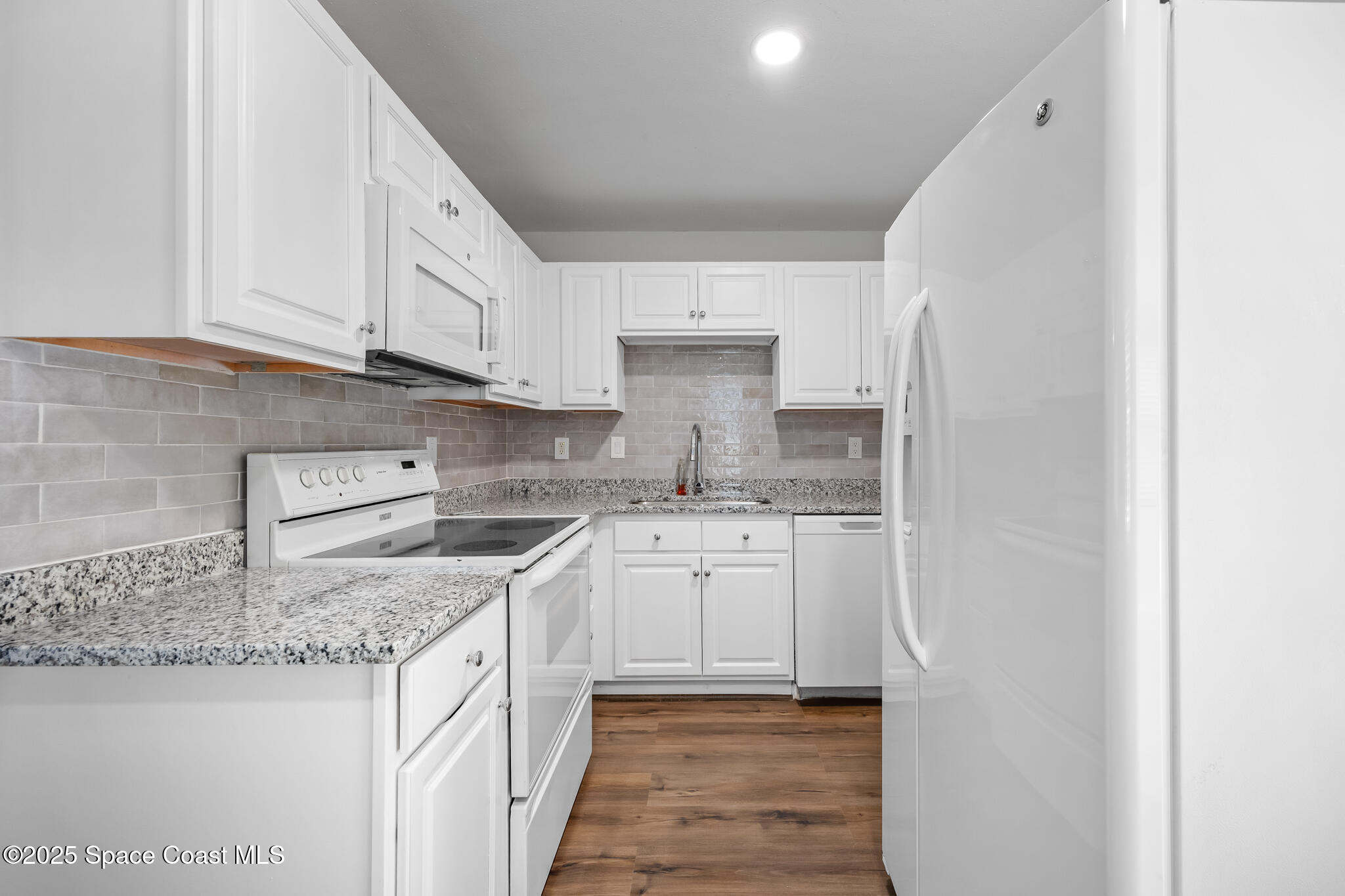 287 Edward Road Melbourne, FL 32904 - Photo 2 of 22 a kitchen with granite countertop white cabinets and white appliances