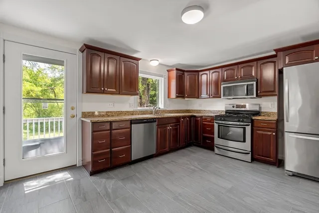 a kitchen with granite countertop wooden floors stainless steel appliances a window and a window