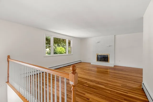 a view of an empty room with window and wooden floor