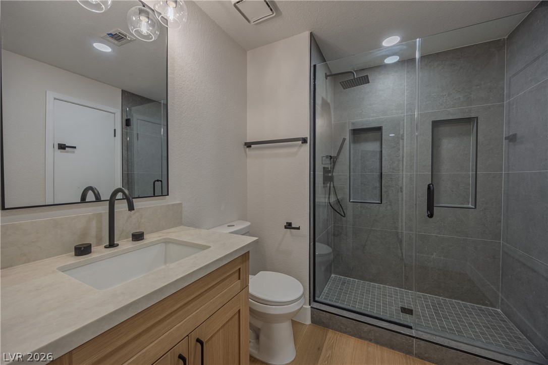 8800 Lusso Las Vegas, NV 89134 - Photo 63 of 85 Bathroom featuring vanity, a stall shower, light wood-style floors, and a textured wall