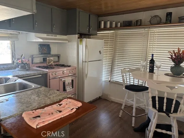 a kitchen with stainless steel appliances kitchen island a table chairs in it and wooden floors