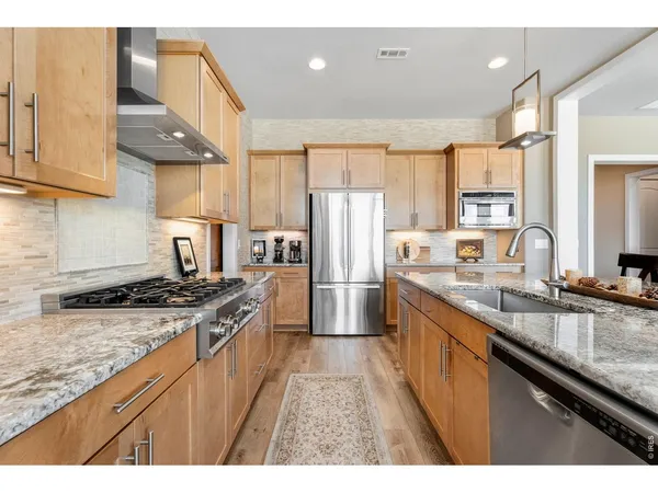 a kitchen with stainless steel appliances granite countertop sink wooden floor dining table and chairs