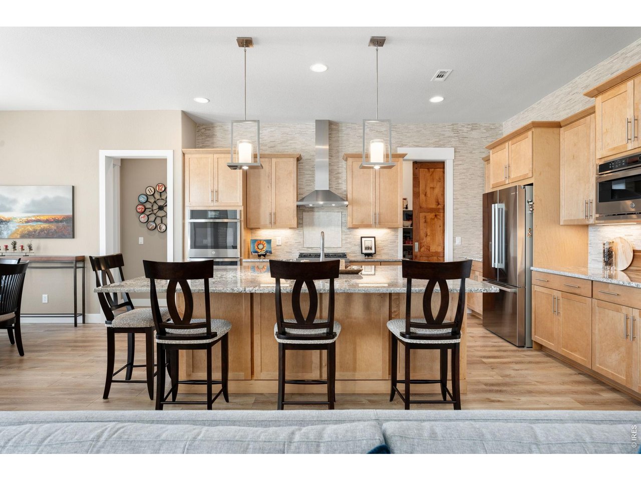 1030 Larimer Ridge Parkway Timnath, CO 80547 - Photo 16 of 38 a kitchen with stainless steel appliances kitchen island granite countertop a dining table chairs refrigerator and microwave