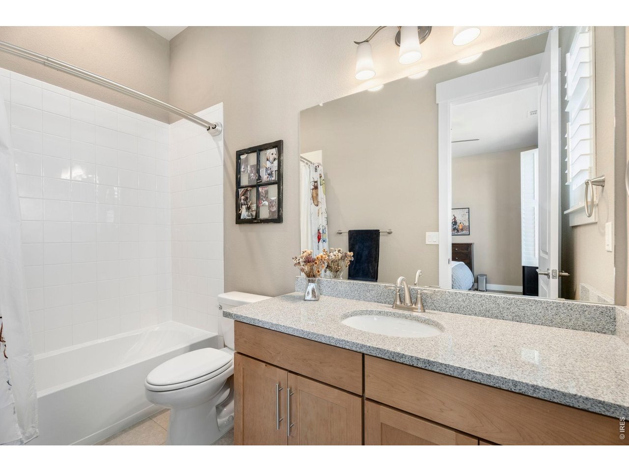 1030 Larimer Ridge Parkway Timnath, CO 80547 - Photo 24 of 38 a bathroom with a granite countertop sink toilet a large mirror a shower and vanity