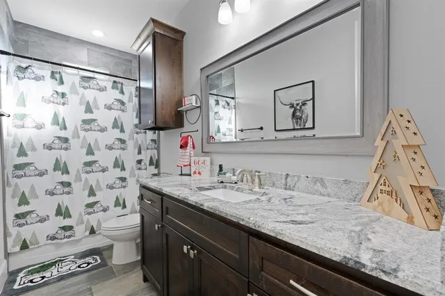 a bathroom with a granite countertop sink a toilet and a mirror