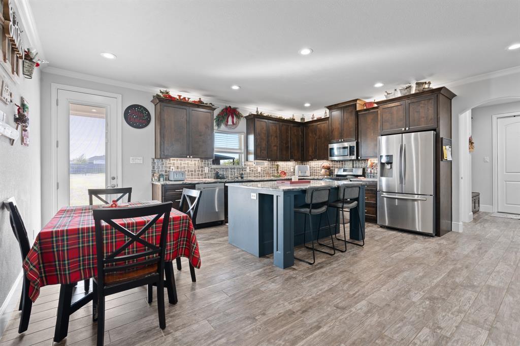 6033 Berry Ridge Lane Joshua, TX 76058 - Photo 6 of 39 a kitchen with stainless steel appliances granite countertop a dining table chairs refrigerator and sink