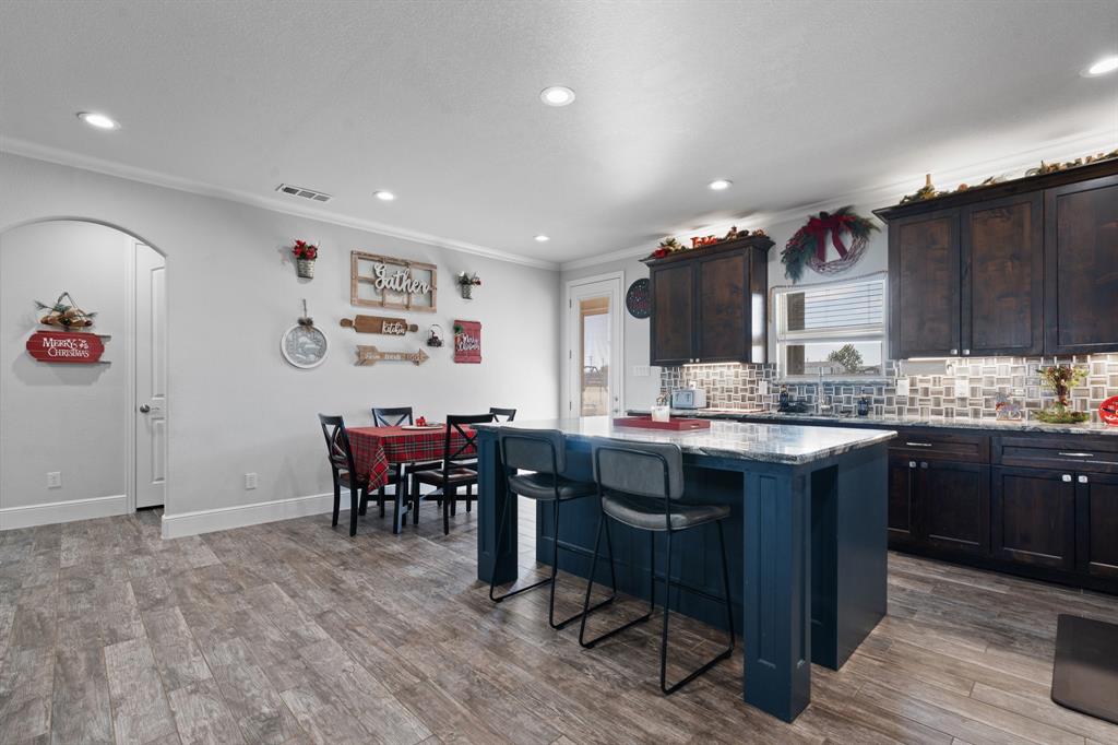 6033 Berry Ridge Lane Joshua, TX 76058 - Photo 7 of 39 a kitchen with kitchen island granite countertop a sink cabinets and wooden floor