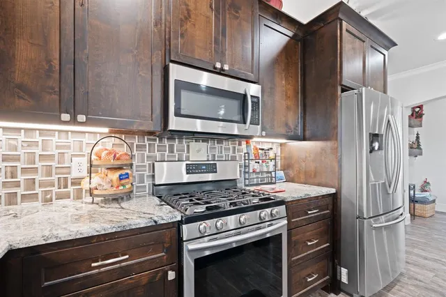 a kitchen with stainless steel appliances granite countertop a stove a sink and a microwave