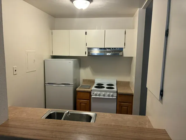 a kitchen with kitchen island a stove a refrigerator and a sink