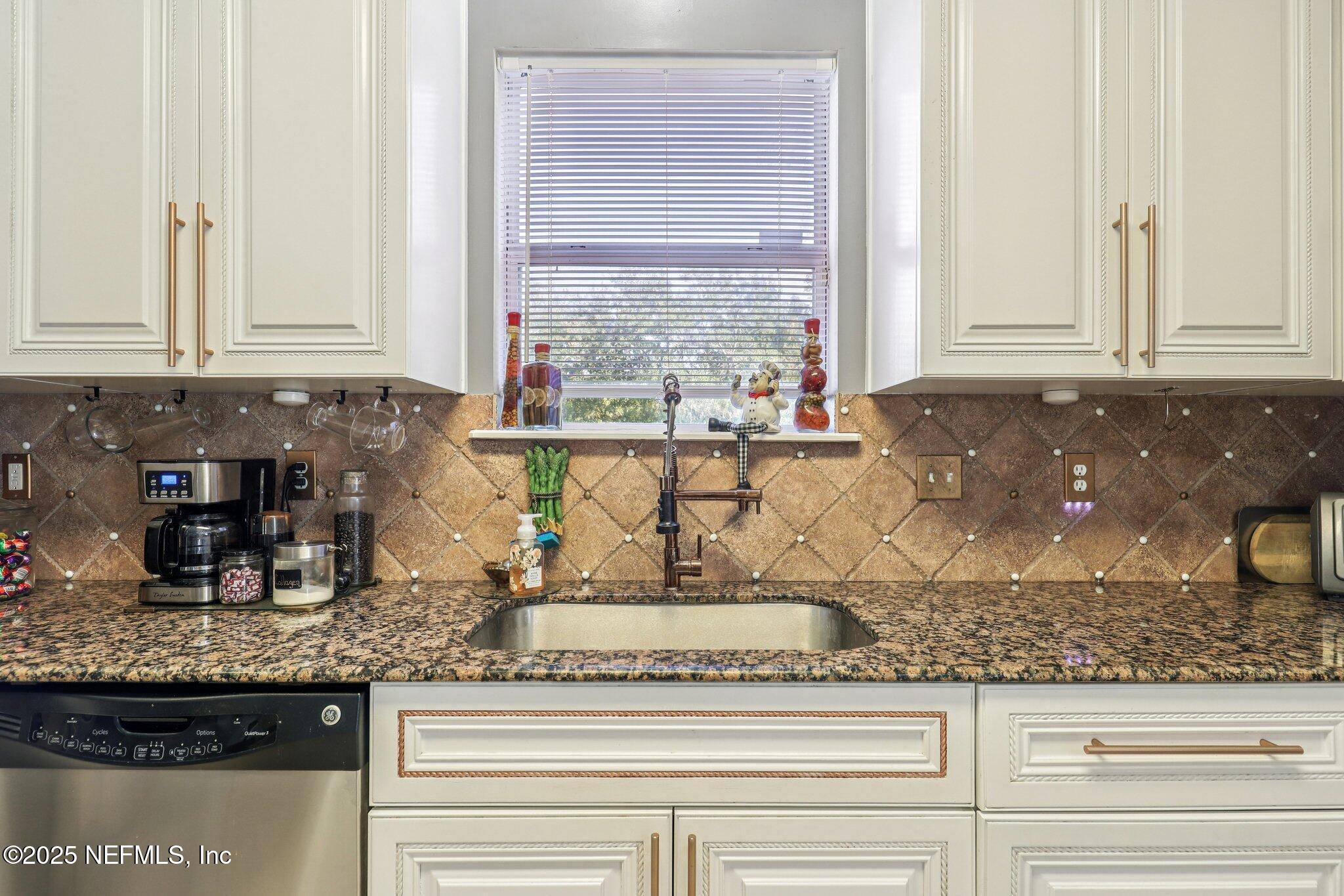 1693 Sanctuary Way Fleming Island, FL 32003 - Photo 12 of 33 a kitchen with granite countertop white cabinets and window