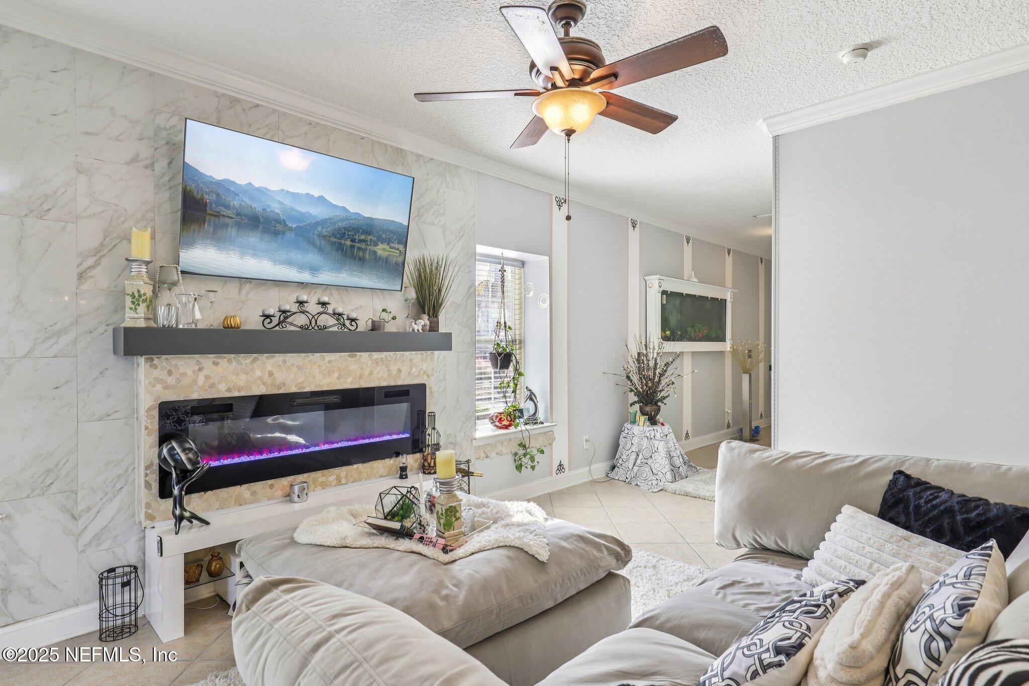 1693 Sanctuary Way Fleming Island, FL 32003 - Photo 5 of 33 a living room with furniture a flat screen tv and a fireplace