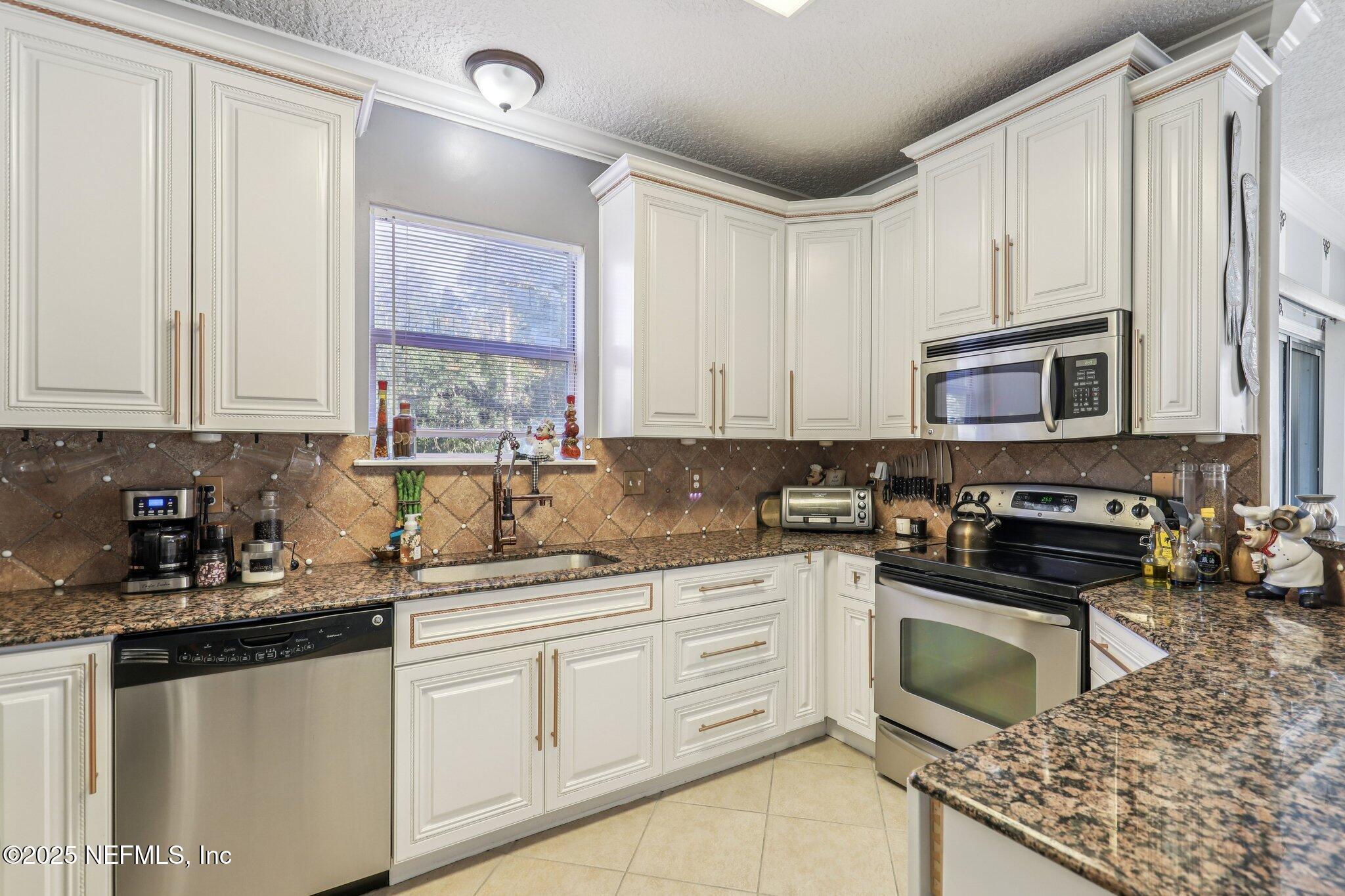 1693 Sanctuary Way Fleming Island, FL 32003 - Photo 10 of 33 a kitchen with stainless steel appliances granite countertop a stove a sink and a microwave