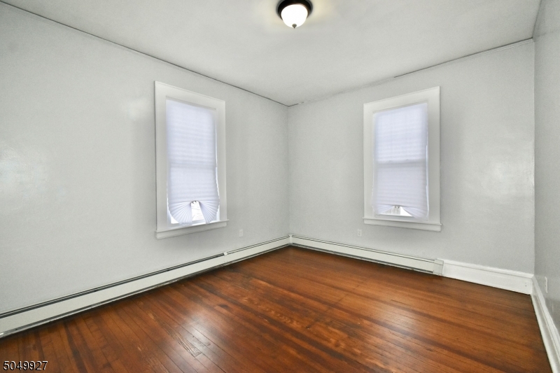 519 Clinton Place, Unit 2R Newark, NJ 07112 - Photo 14 of 15 an empty room with wooden floor and windows