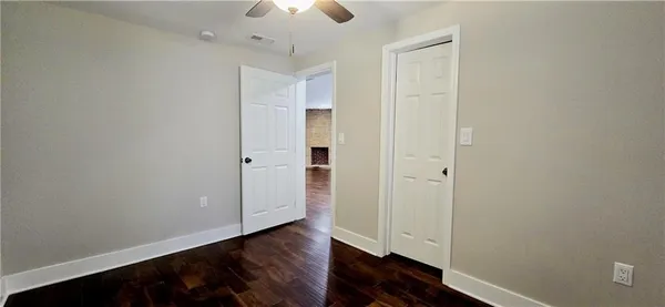 an empty room with wooden floor closet and windows