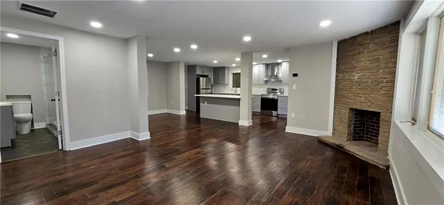 a living room with stainless steel appliances furniture a fireplace and wooden floor