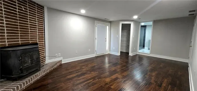 a view of an empty room with wooden floor and a fireplace