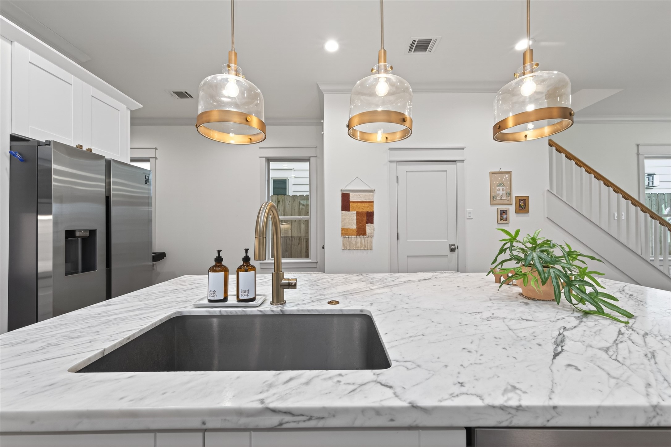 515 West 25th Street, Unit 1 Houston, TX 77008 - Photo 15 of 44 Kitchen showcases job-built Shaker-style cabinets with crown-molding lift, soft-close drawers and doors, antique brass pull handles and square knobs, and under-cabinet lighting that brightens workspaces. Door leads to closet under the stairs and hallway leads to the walk-in pantry, and 1st floor bedroom suite.