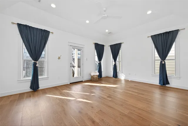 an empty room with wooden floor & windows and bathroom