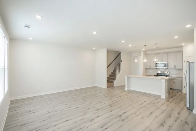a view of kitchen with kitchen island microwave oven stove and white cabinets with wooden floor