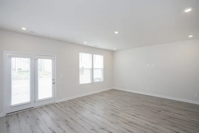 an empty room with wooden floor and windows