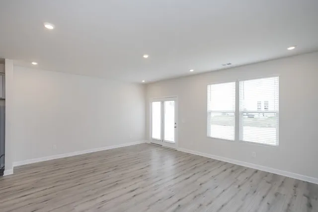 an empty room with wooden floor and windows